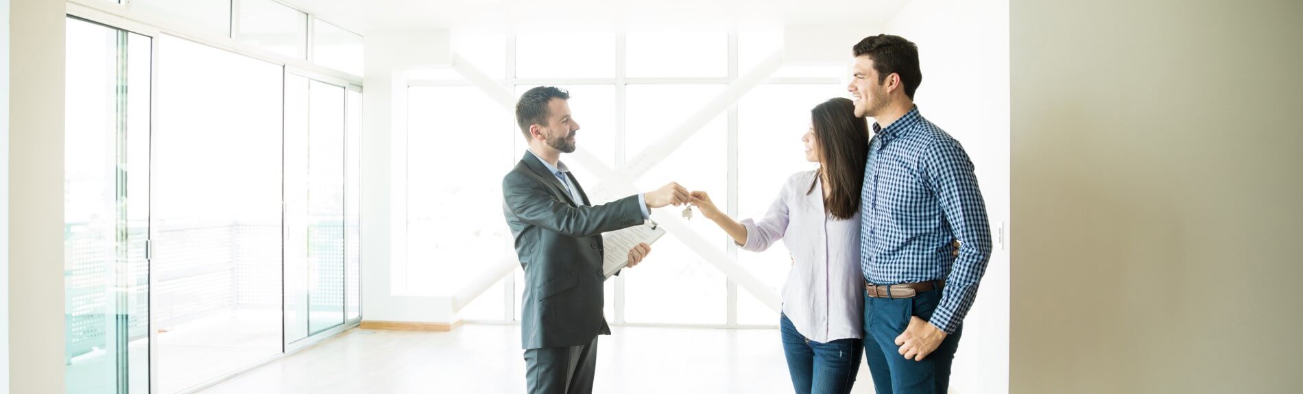 A man in suit hands keys to a couple